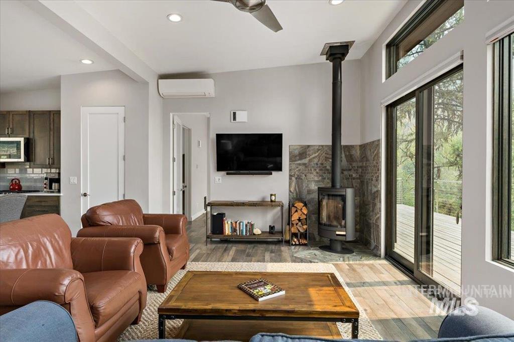 Living area with a wood stove, light wood-type flooring, recessed lighting, a ceiling fan, and a wall mounted AC