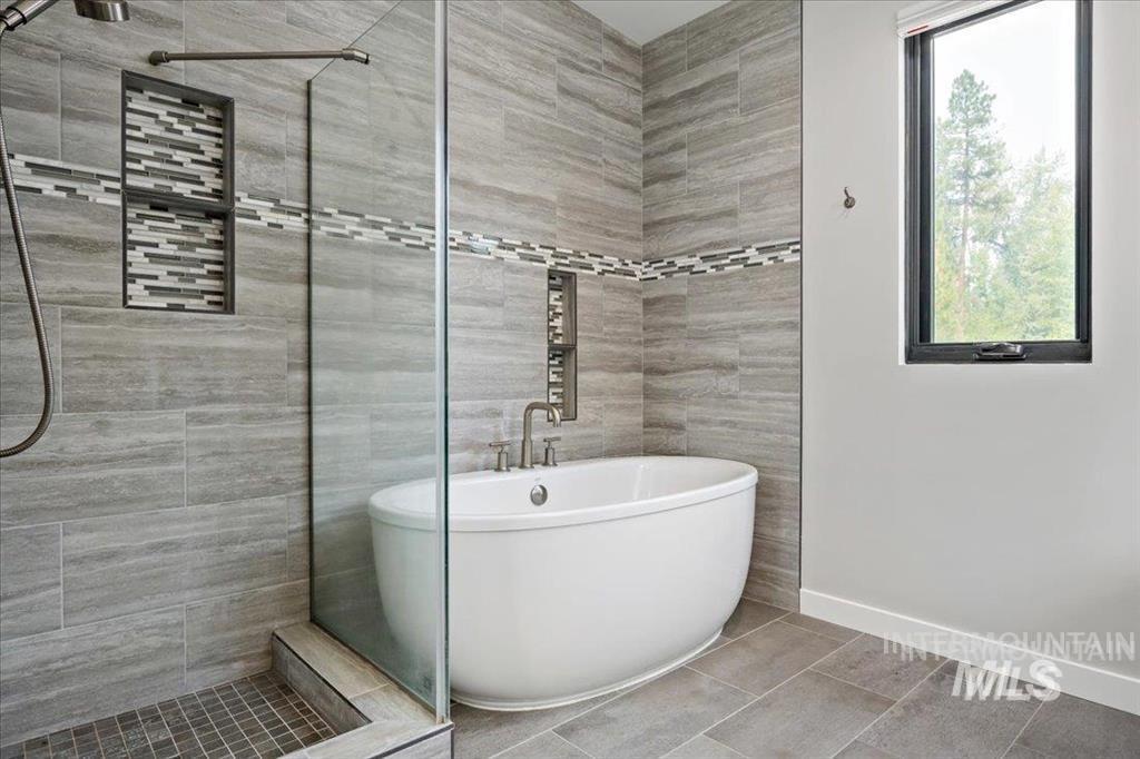 Bathroom featuring a tile shower, a freestanding bath, tile walls, and tile patterned floors