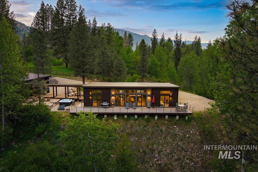 Back of property at dusk featuring a deck with mountain view and a forest view