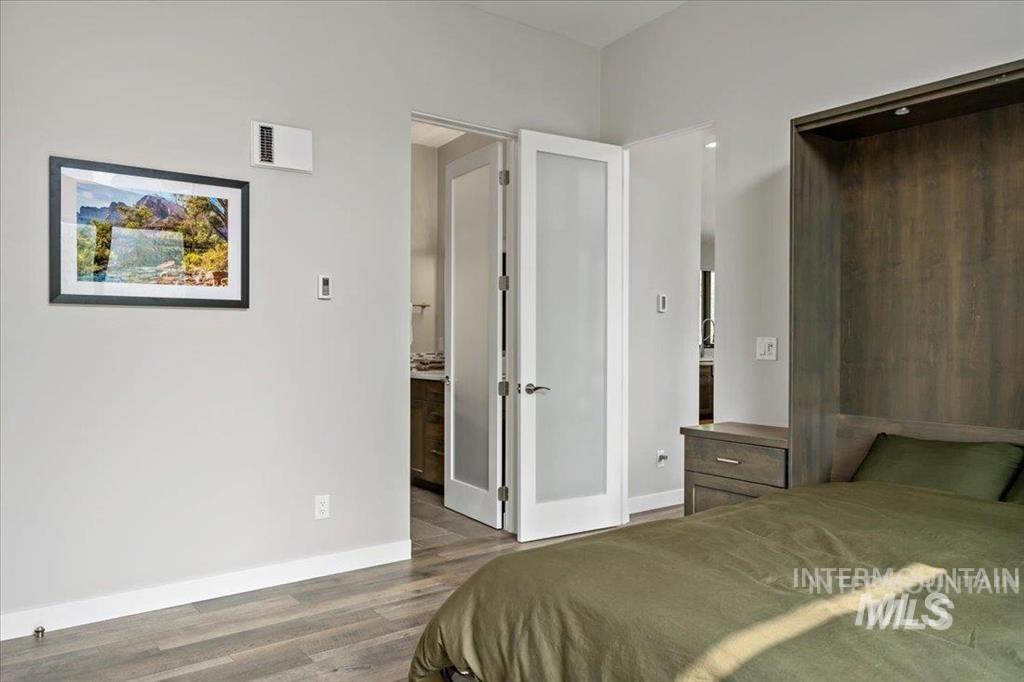 Bedroom with dark wood finished floors and connected bathroom