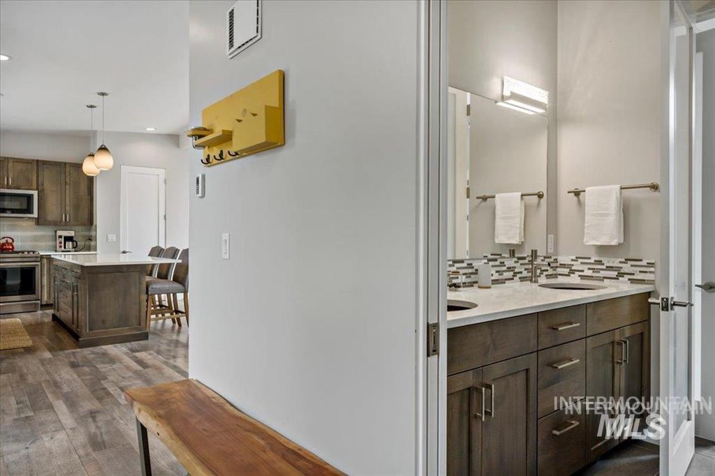 Kitchen with decorative backsplash, dark brown cabinetry, dark wood-style flooring, stainless steel appliances, and recessed lighting
