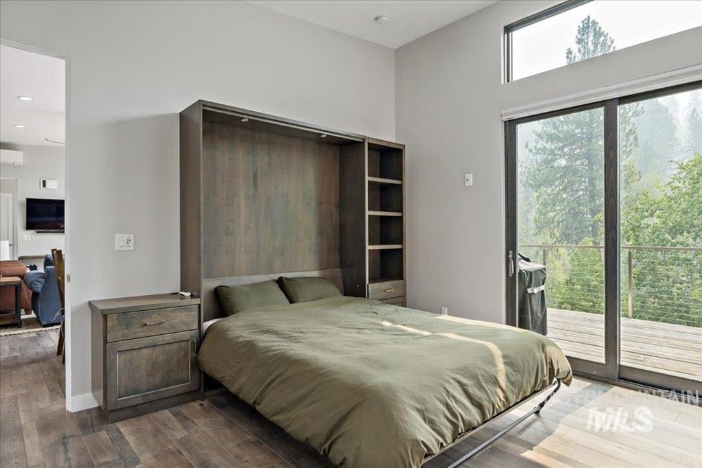 Bedroom featuring wood finished floors, access to outside, and a wall mounted air conditioner