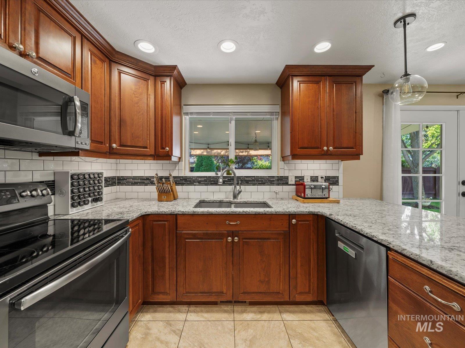 Kitchen featuring stainless steel appliances, light stone counters, a textured ceiling, recessed lighting, and tasteful backsplash