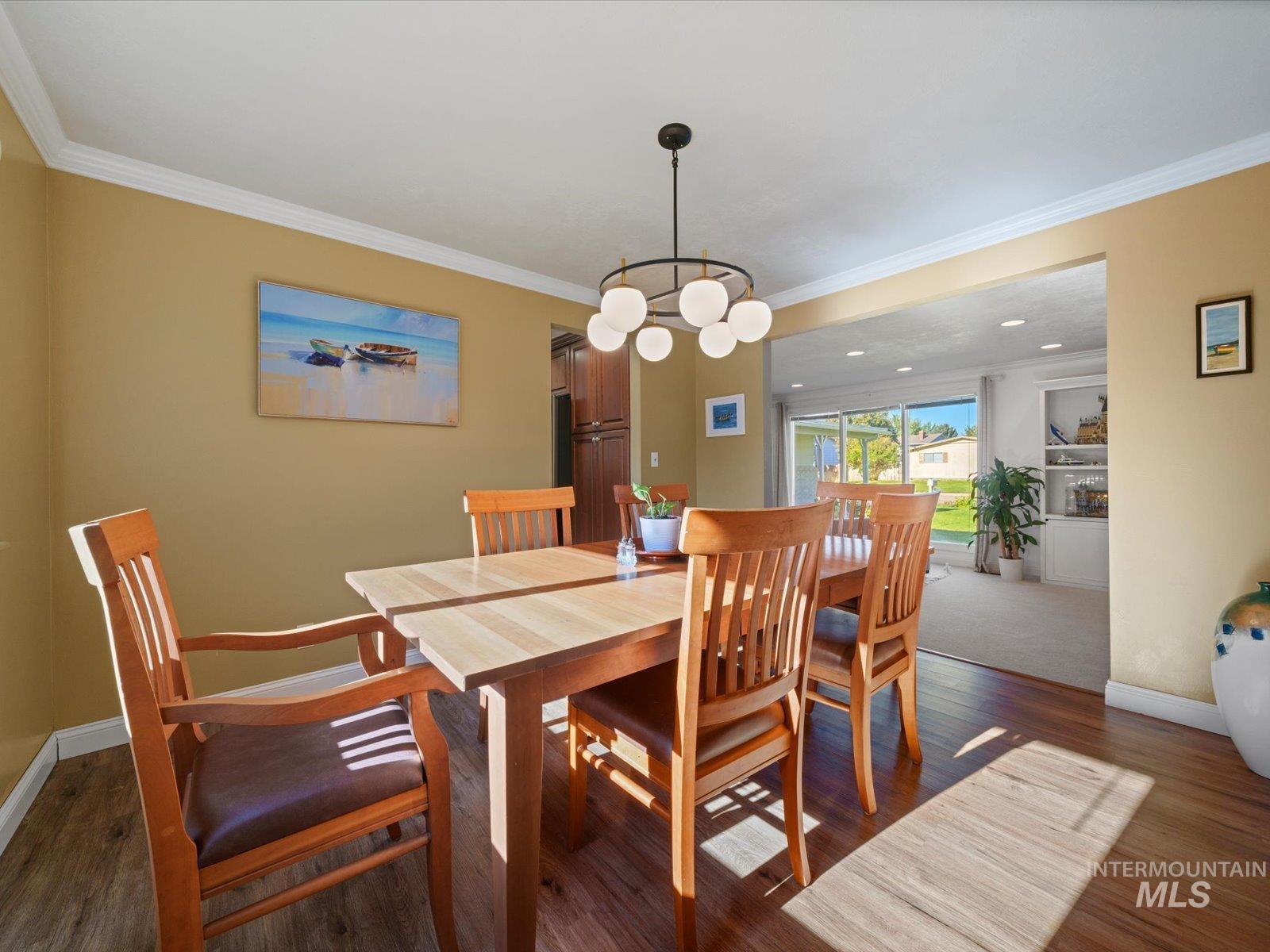 Dining area featuring ornamental molding, dark wood-style floors, and a chandelier