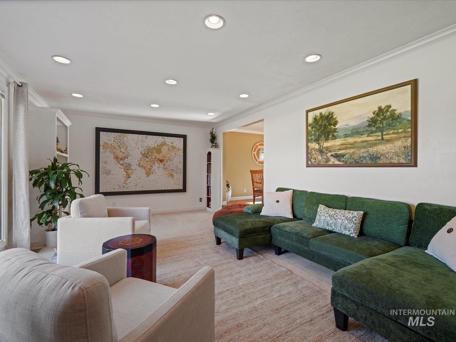 Carpeted living area with crown molding and recessed lighting