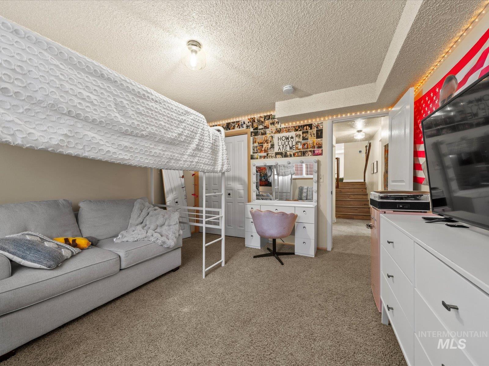 Bedroom featuring light carpet, a textured ceiling, and a closet