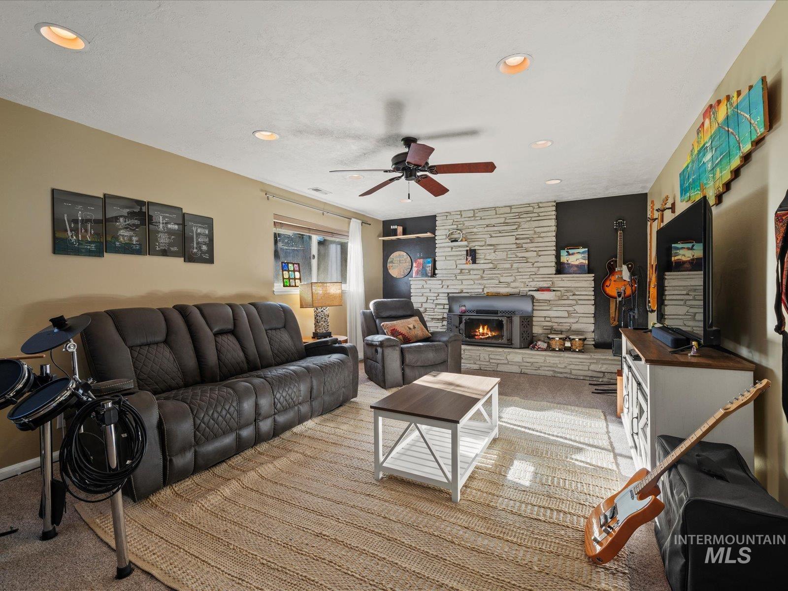 Carpeted living area with ceiling fan, a fireplace, recessed lighting, and a textured ceiling
