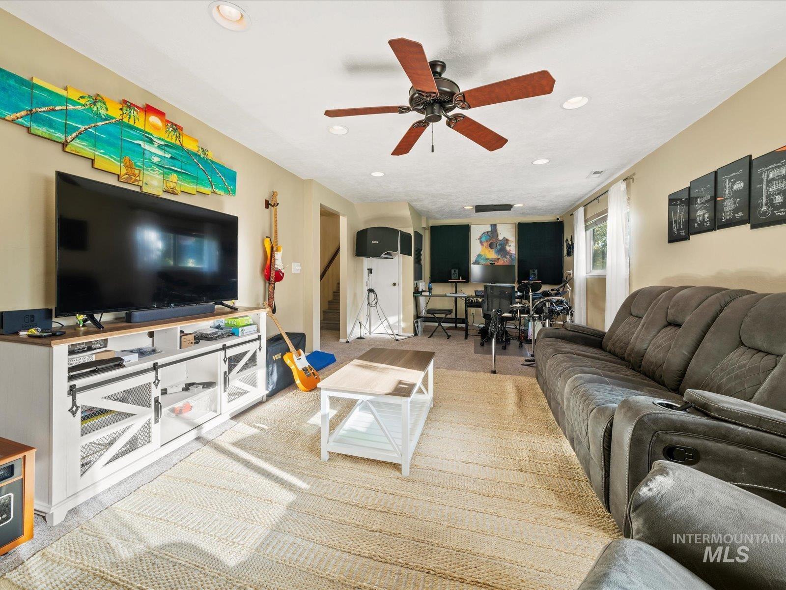 Living room featuring light colored carpet, arched walkways, recessed lighting, and ceiling fan