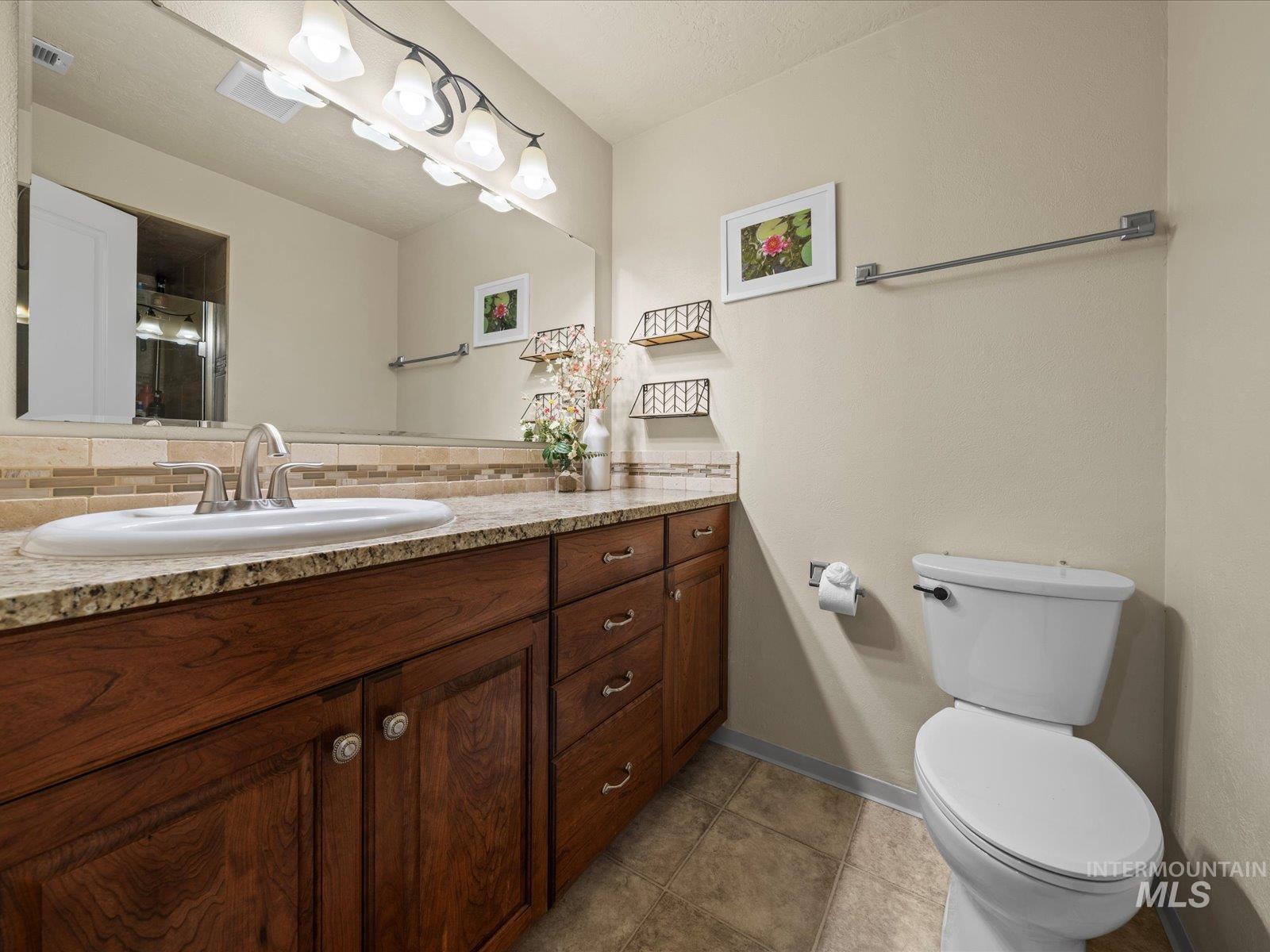 Bathroom featuring vanity, dark tile patterned floors, and decorative backsplash