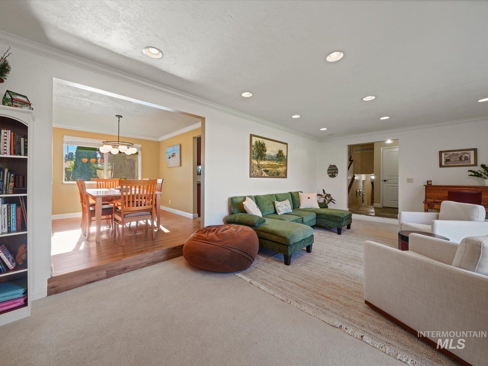 Carpeted living area featuring crown molding, recessed lighting, wood finished floors, a chandelier, and a textured ceiling