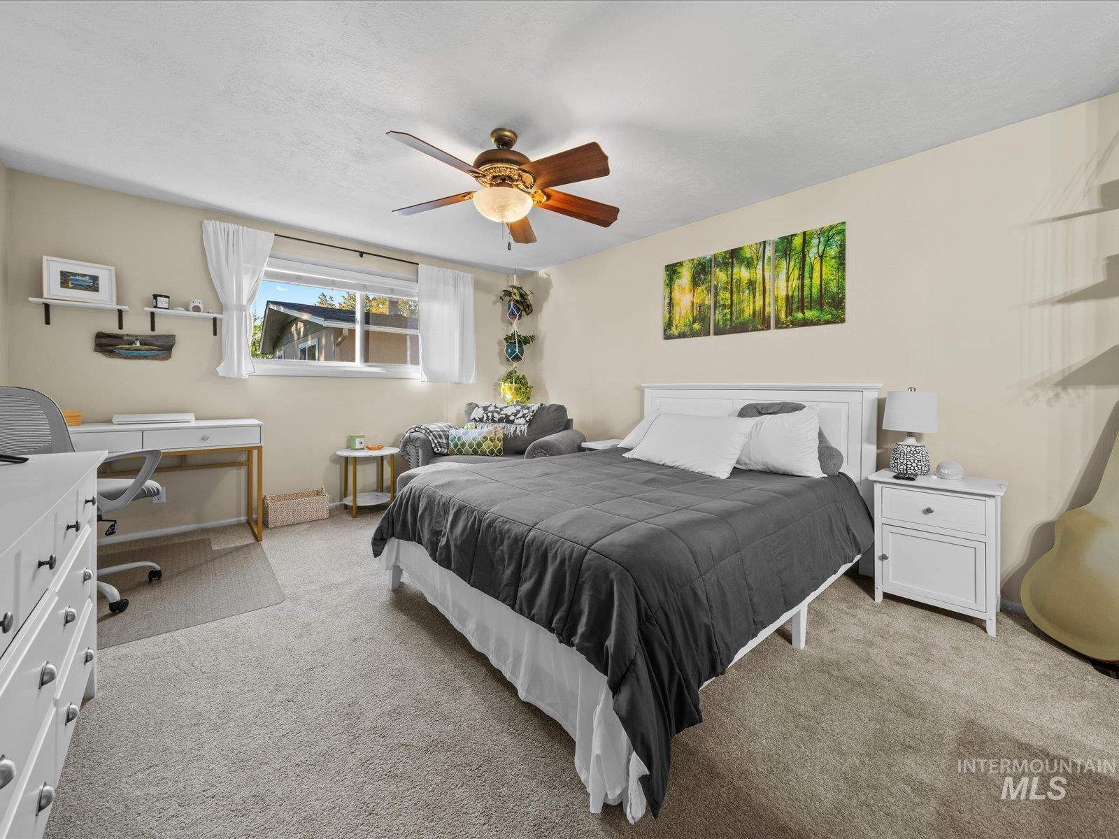 Bedroom featuring light colored carpet, ceiling fan, and a desk