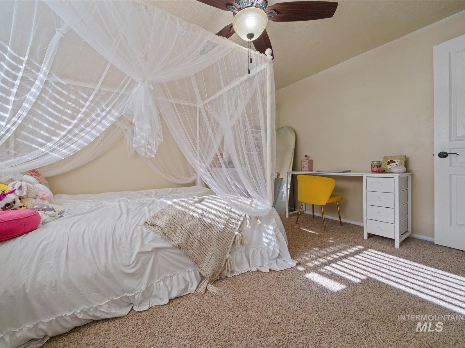 Carpeted bedroom with an office area and ceiling fan