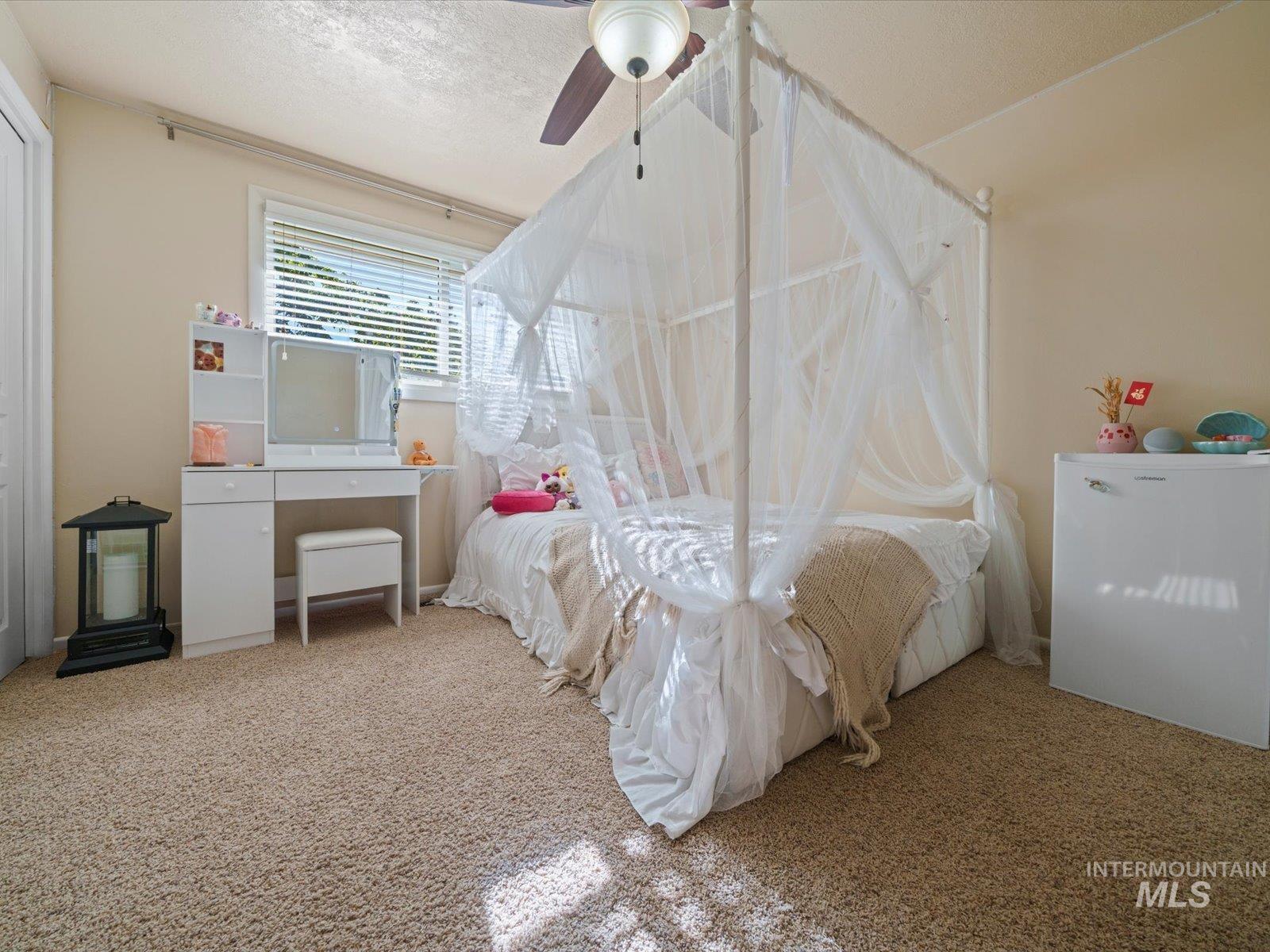 Bedroom with carpet flooring, a textured ceiling, and ceiling fan