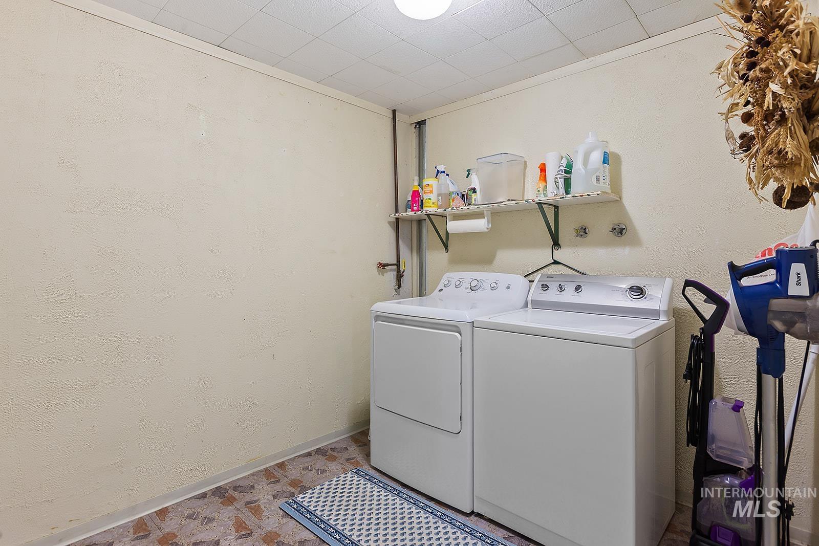 Laundry area featuring a textured wall and washer and clothes dryer