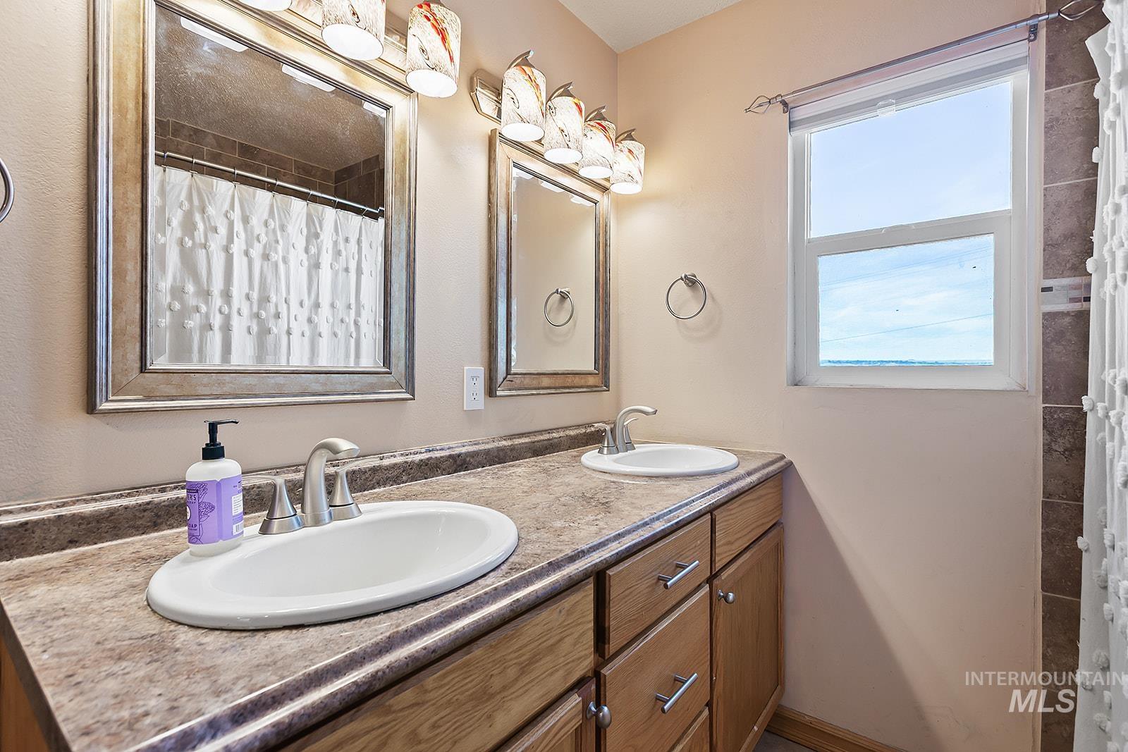 Full bathroom with double vanity and a shower with shower curtain