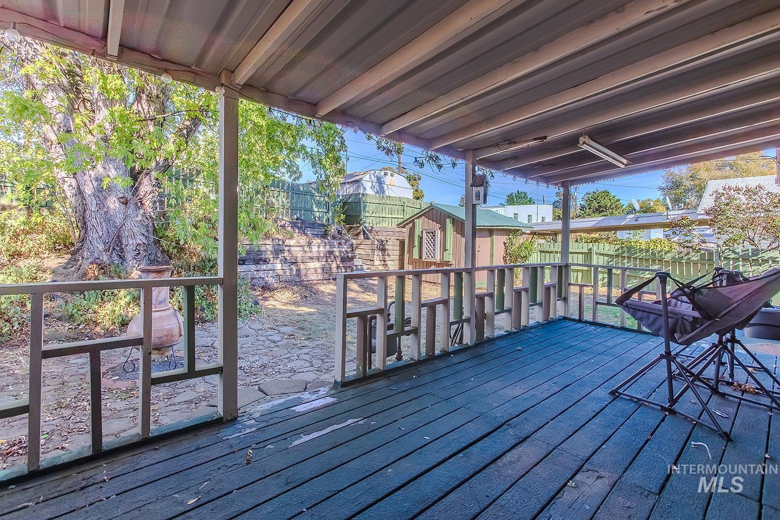 Wooden terrace featuring a fenced backyard and a shed