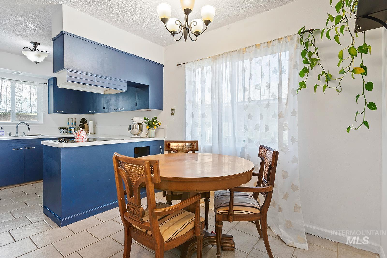 Dining room featuring a textured ceiling, a chandelier, and light tile patterned flooring