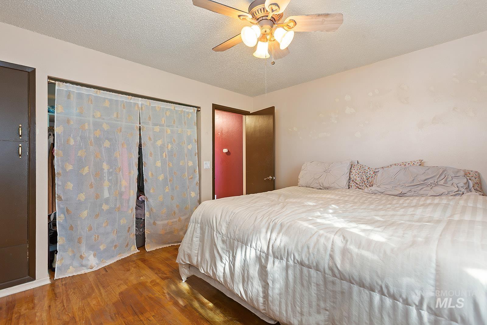 Bedroom with wood finished floors, a textured ceiling, and ceiling fan