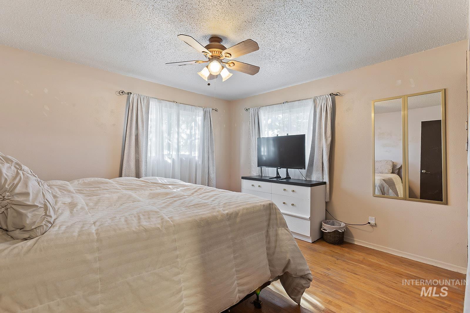 Bedroom featuring light wood finished floors, a ceiling fan, and a textured ceiling