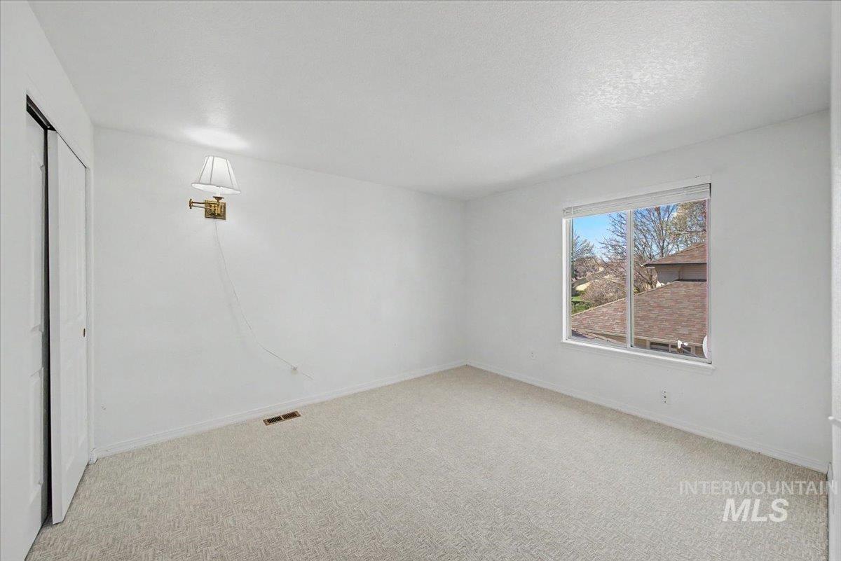 Unfurnished bedroom featuring light carpet, a closet, and a textured ceiling