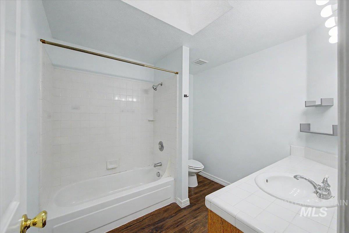 Full bathroom featuring vanity, dark wood finished floors, washtub / shower combination, and a textured ceiling
