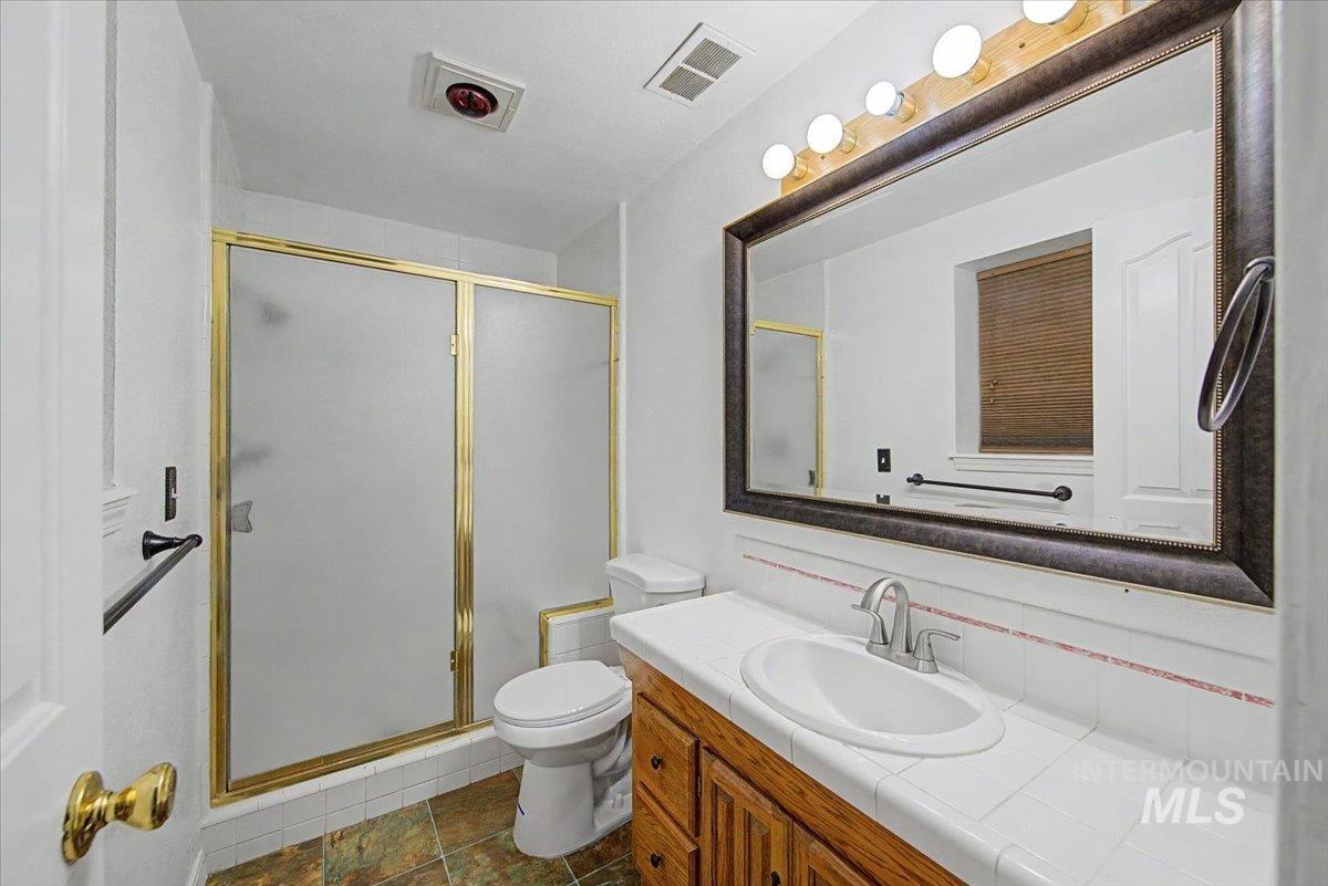 Full bath featuring vanity, a stall shower, and dark tile patterned floors