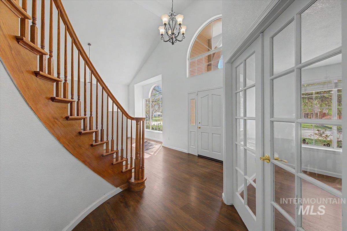 Foyer entrance featuring dark wood-type flooring, lofted ceiling, a chandelier, and french doors