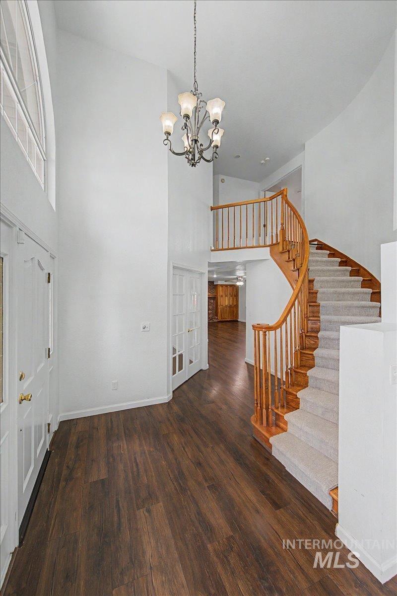 Unfurnished dining area with a high ceiling, dark wood finished floors, and suspended lighting