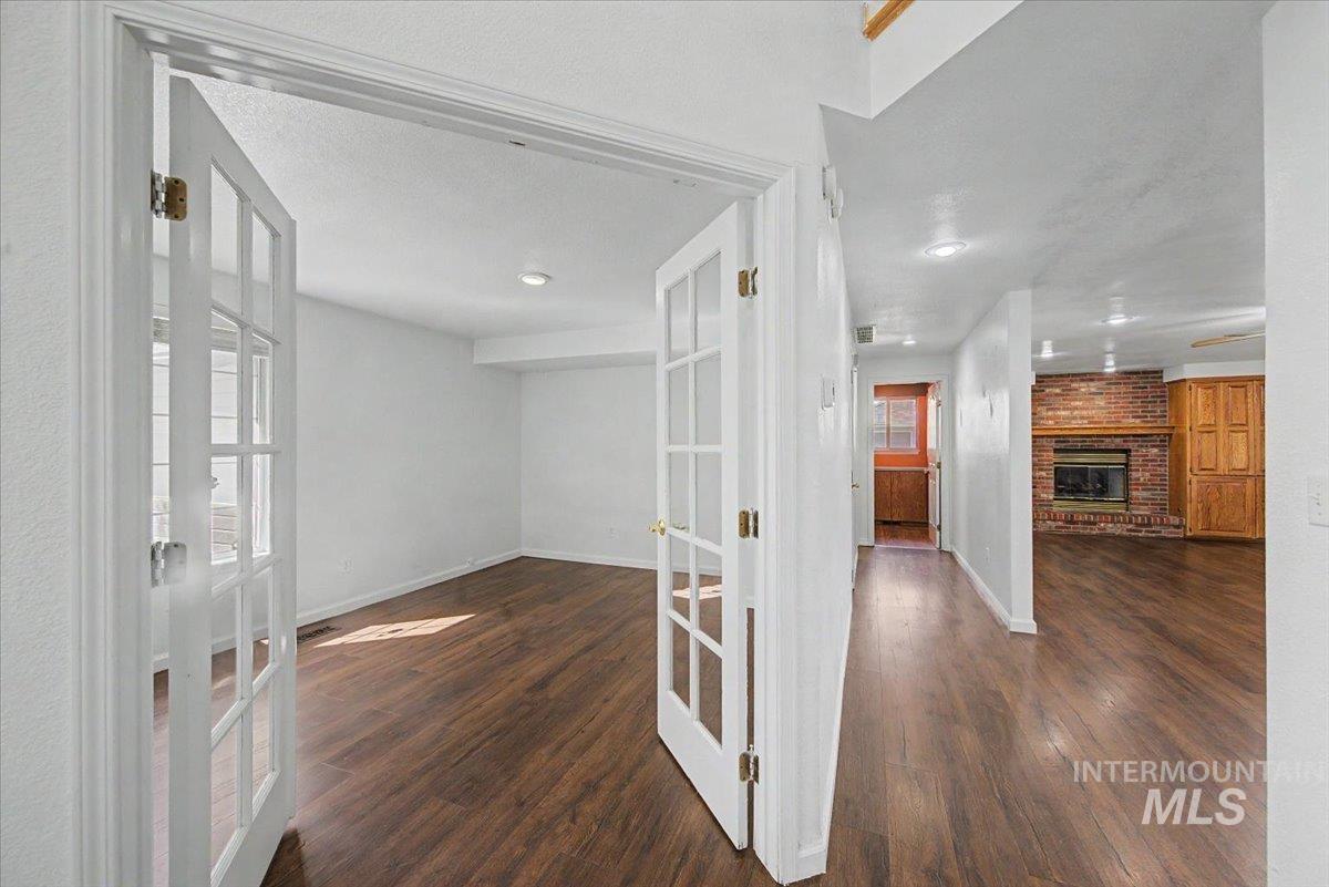 Hallway with french doors and dark wood-style flooring