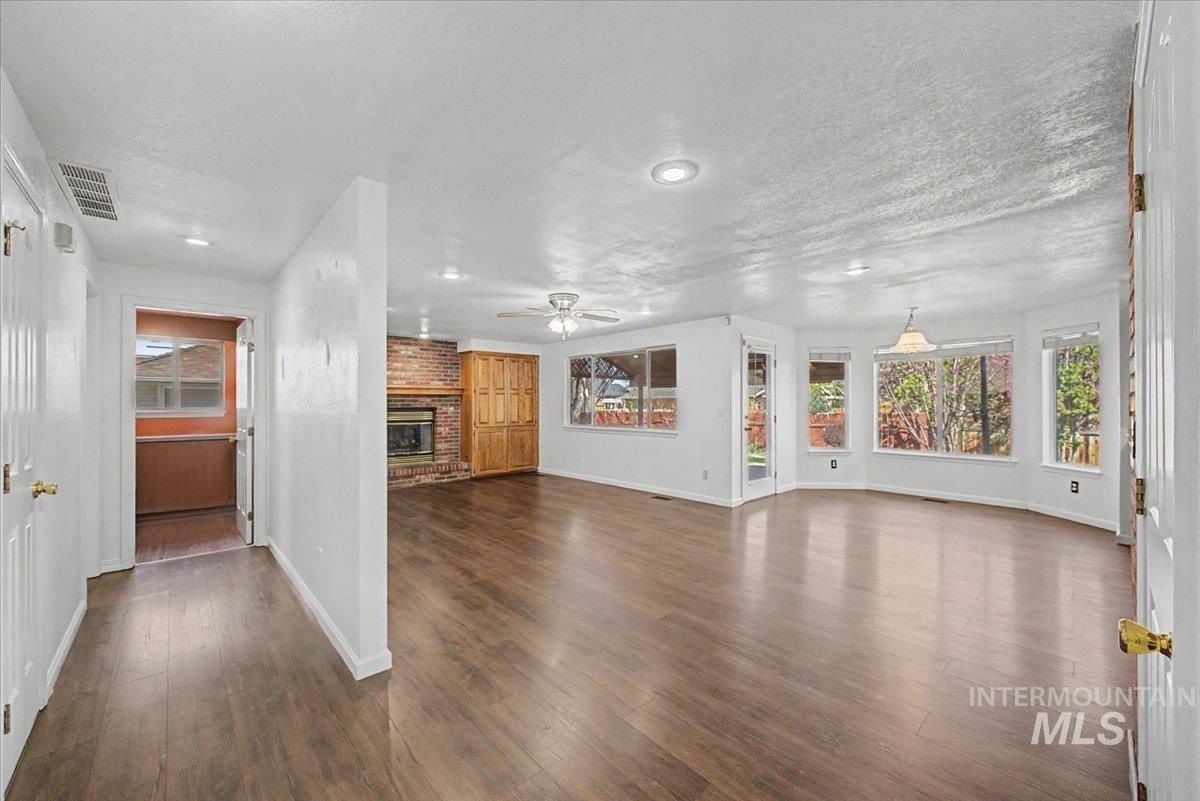 Unfurnished living room featuring a fireplace, dark wood-style flooring, recessed lighting, a textured ceiling, and a ceiling fan