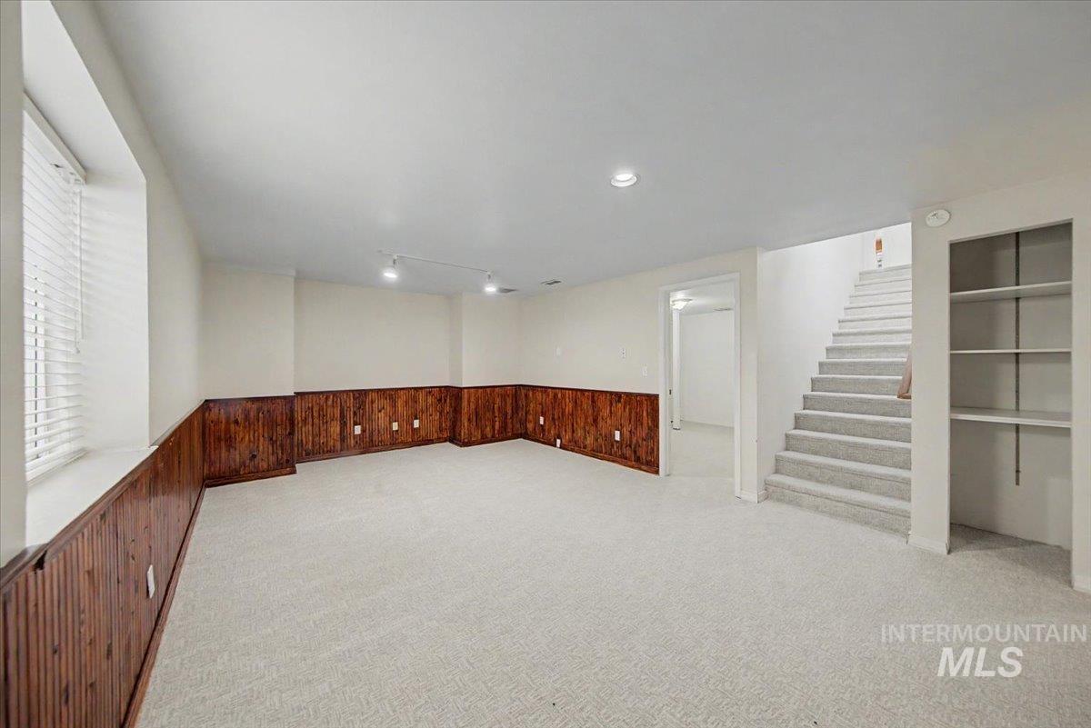 Basement featuring a wainscoted wall, wood walls, and light colored carpet