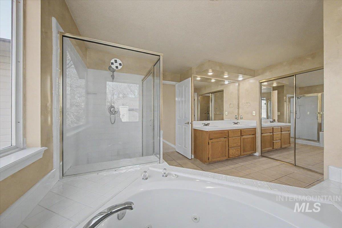 Bathroom featuring vanity, a shower stall, and a whirlpool tub