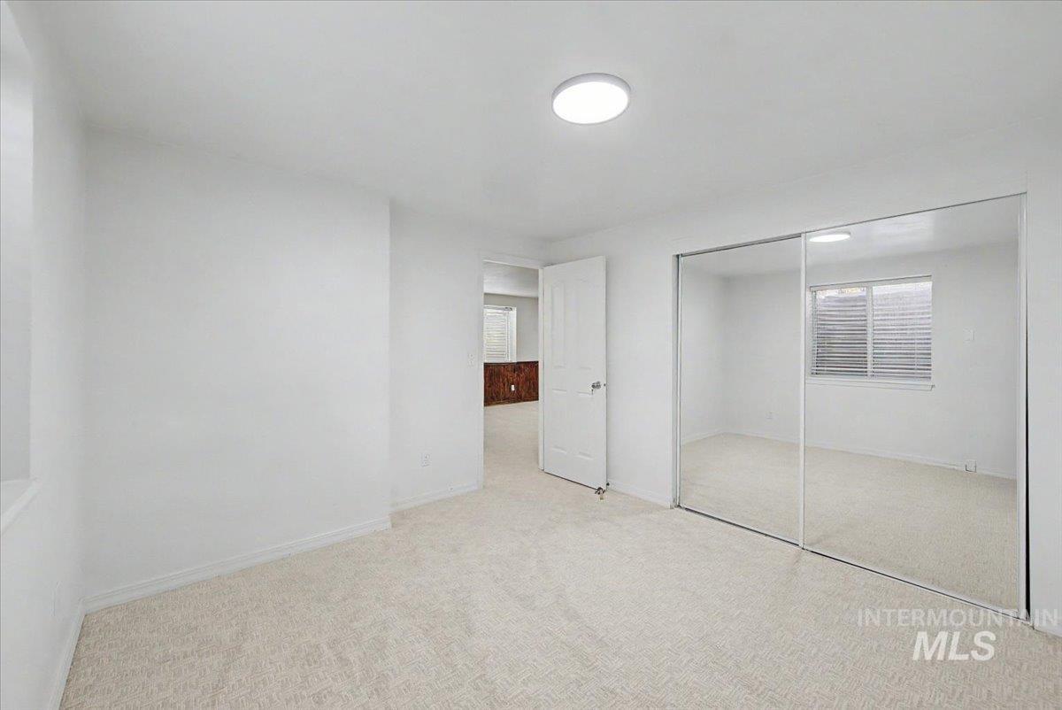 Unfurnished bedroom with light carpet and a closet