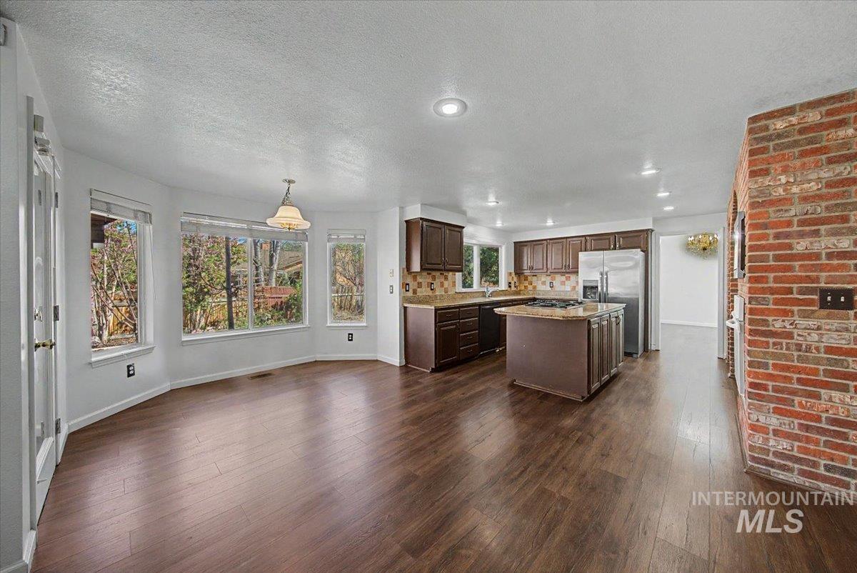 Kitchen featuring a center island, dark wood finish cabinetry, dark wood-style flooring, stainless steel fridge, and a textured ceiling