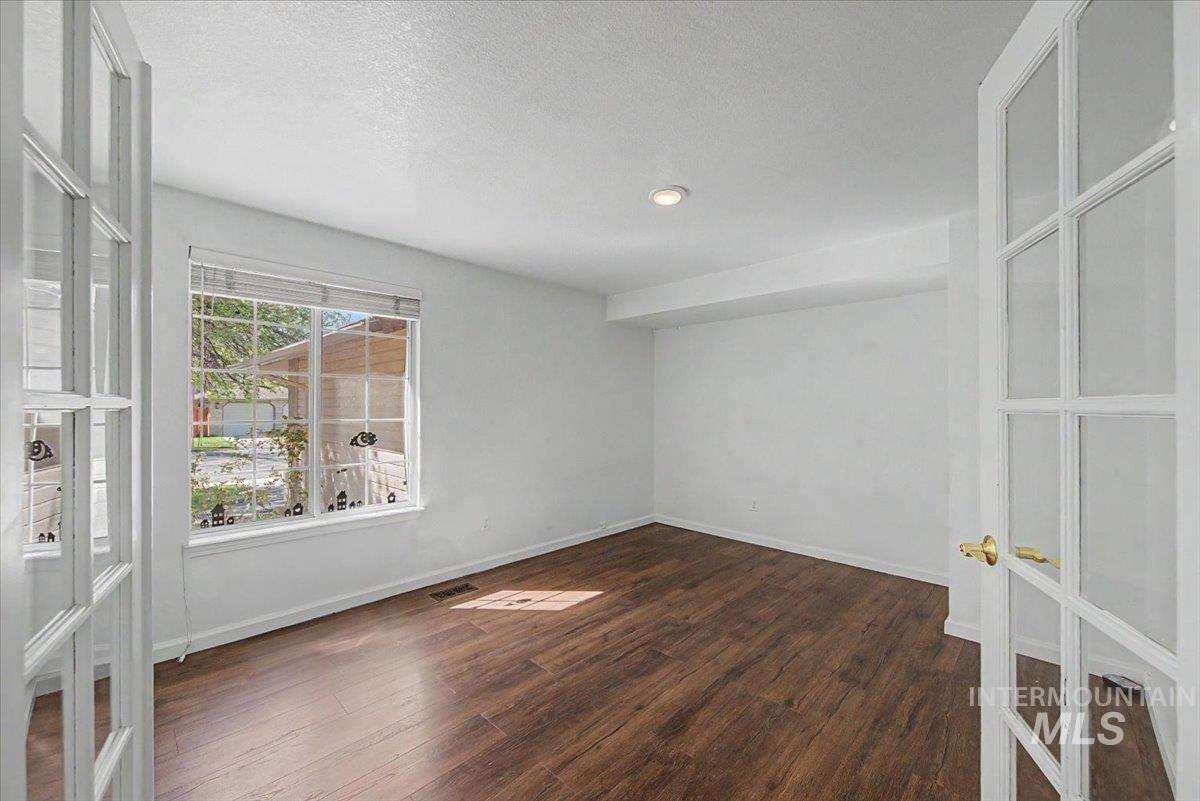 Empty room featuring dark wood-style flooring and a textured ceiling