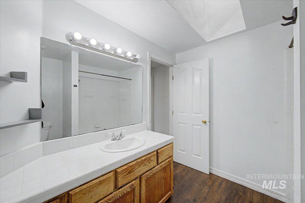 Full bathroom featuring vanity, dark wood-style flooring, and a shower