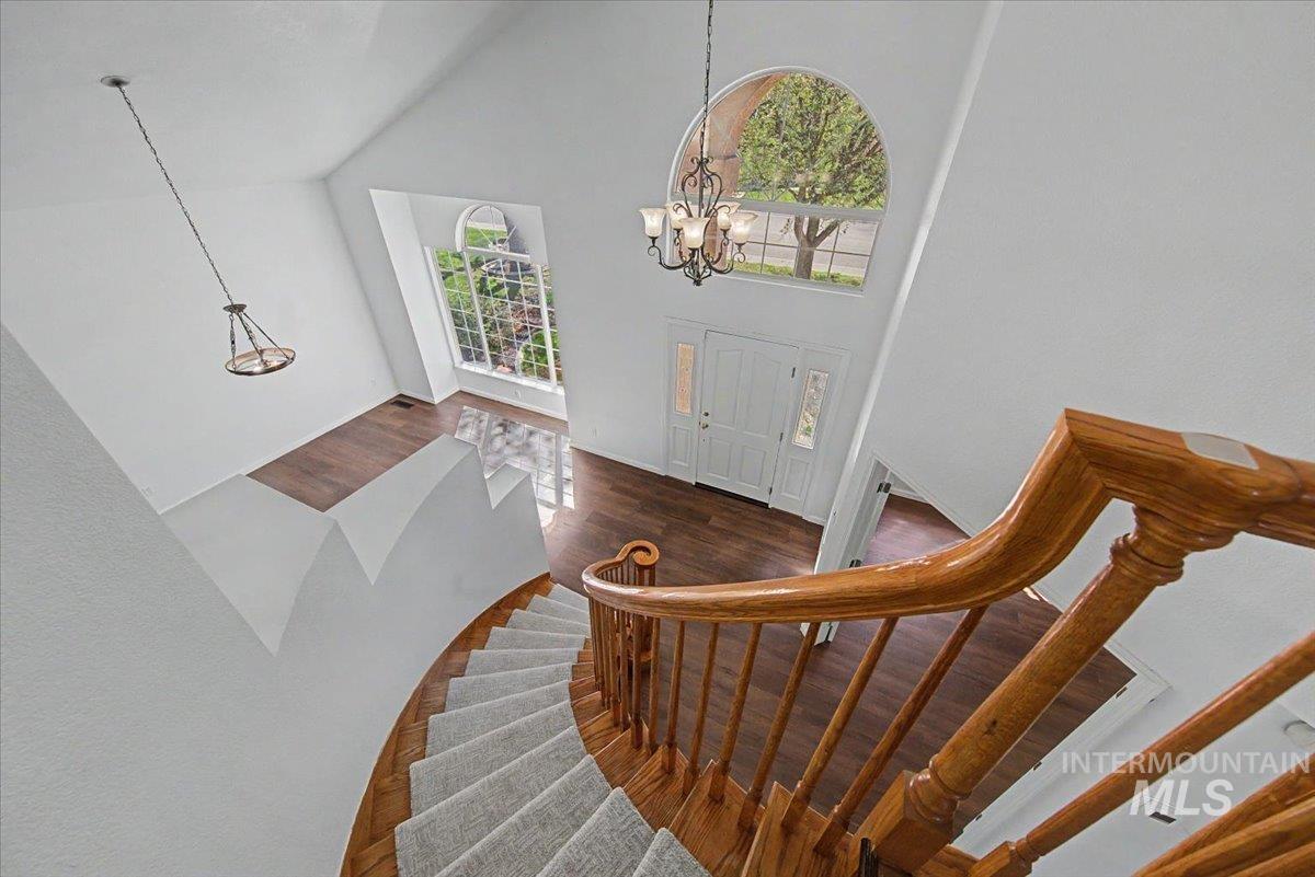 Foyer featuring dark wood-type flooring, suspended lighting, and lofted ceiling