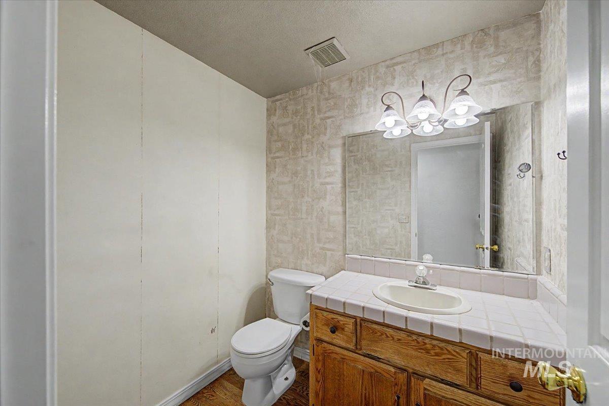 Bathroom featuring vanity, a textured ceiling, dark wood-style floors, and suspended lighting