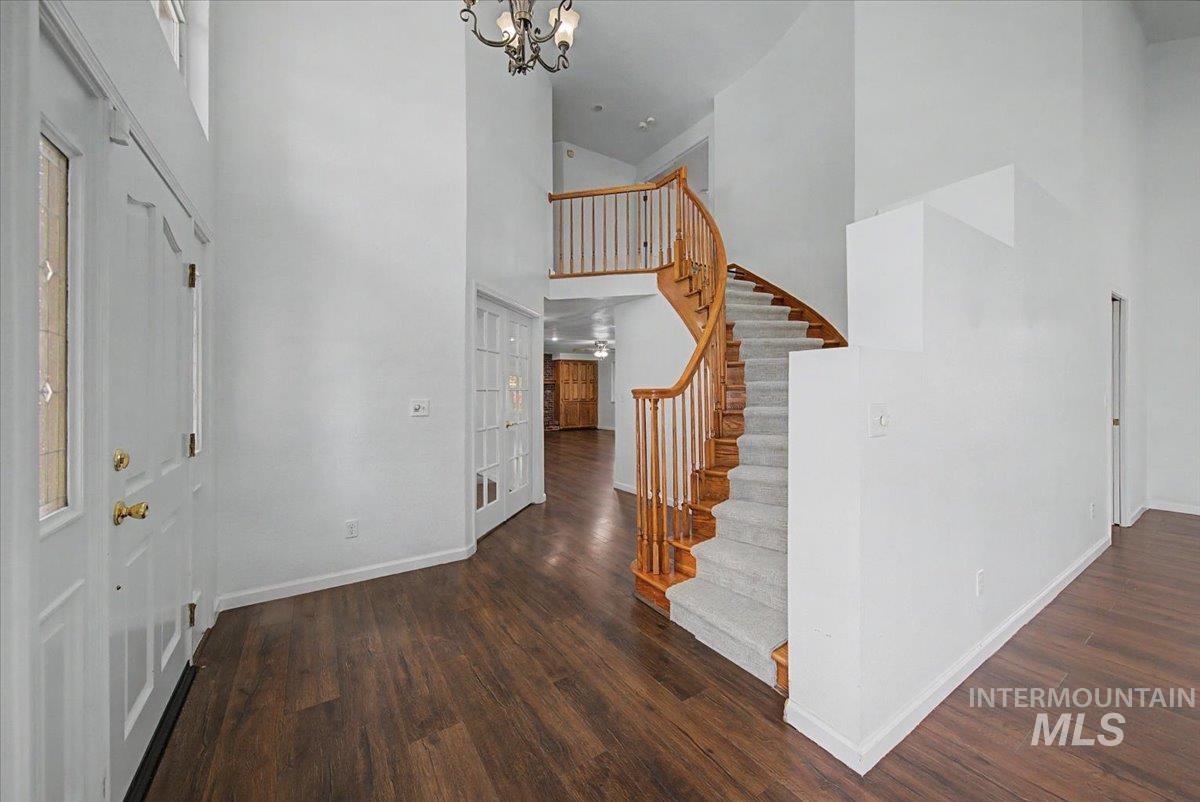 Foyer entrance featuring dark wood finished floors, hanging lights, a high ceiling, and french doors