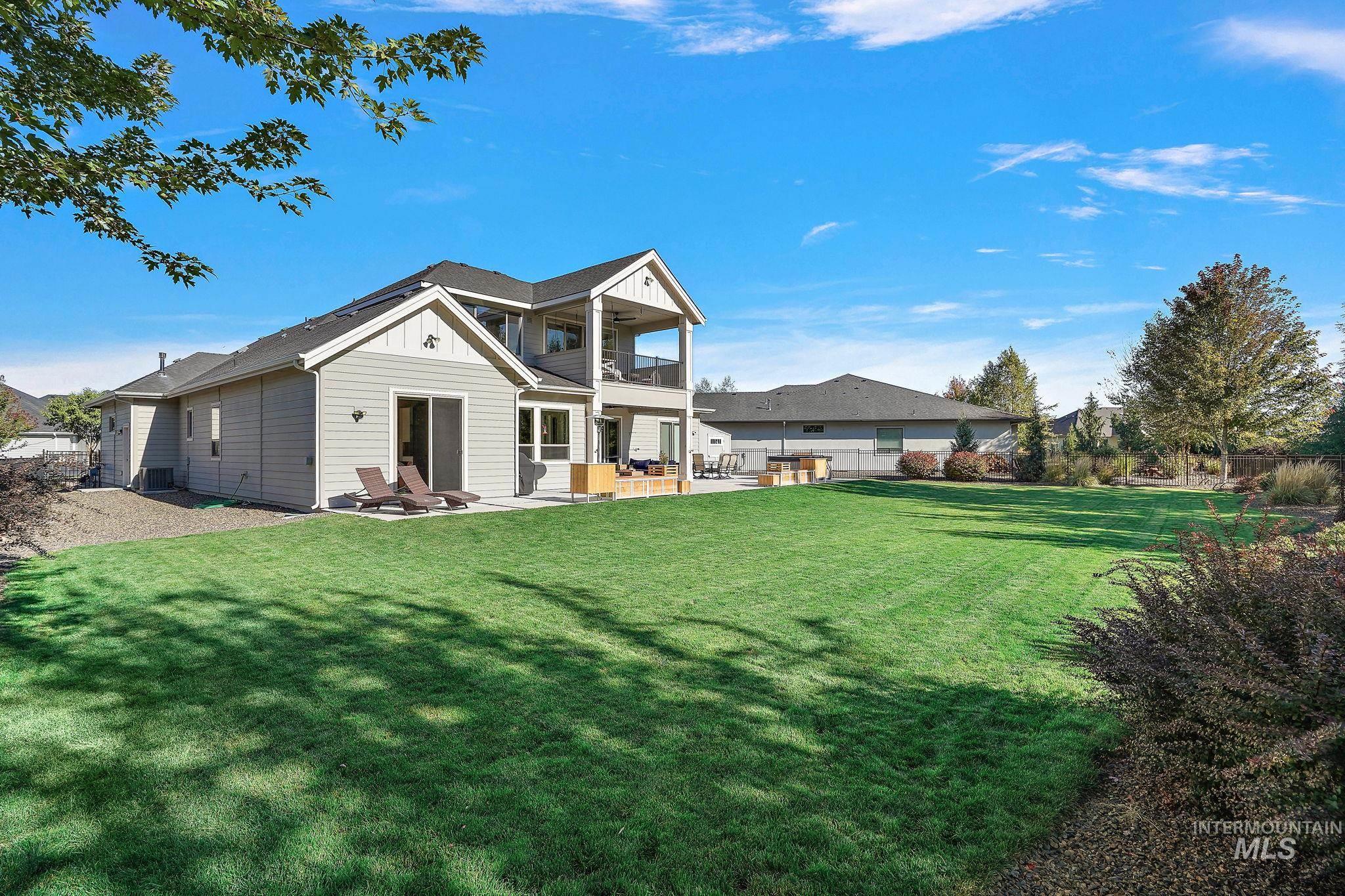 Rear view of house with board and batten siding, a balcony, a patio area, and a fenced backyard