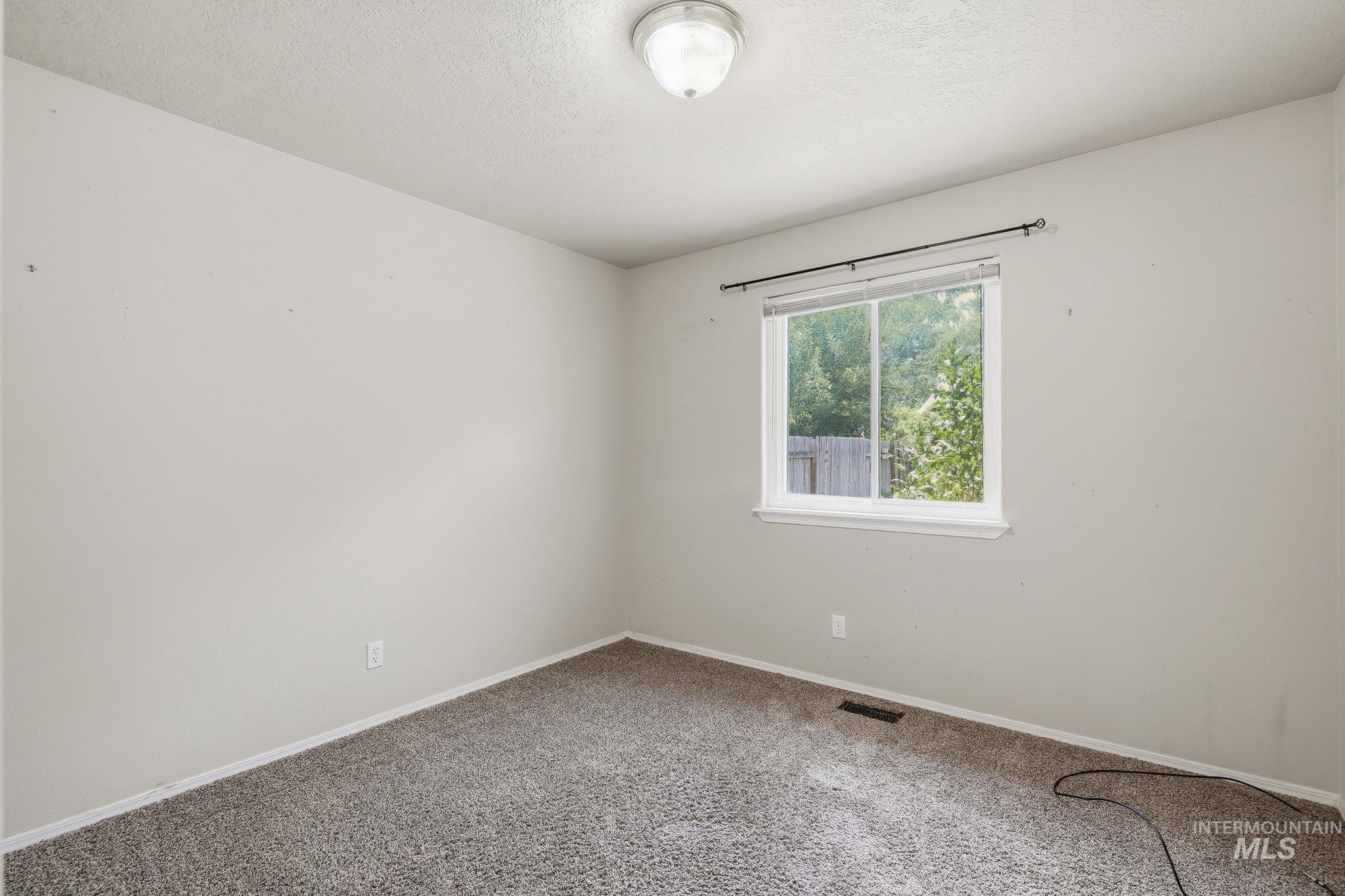 Carpeted room featuring light gray walls, a single window with white trim, and a ceiling-mounted light fixture