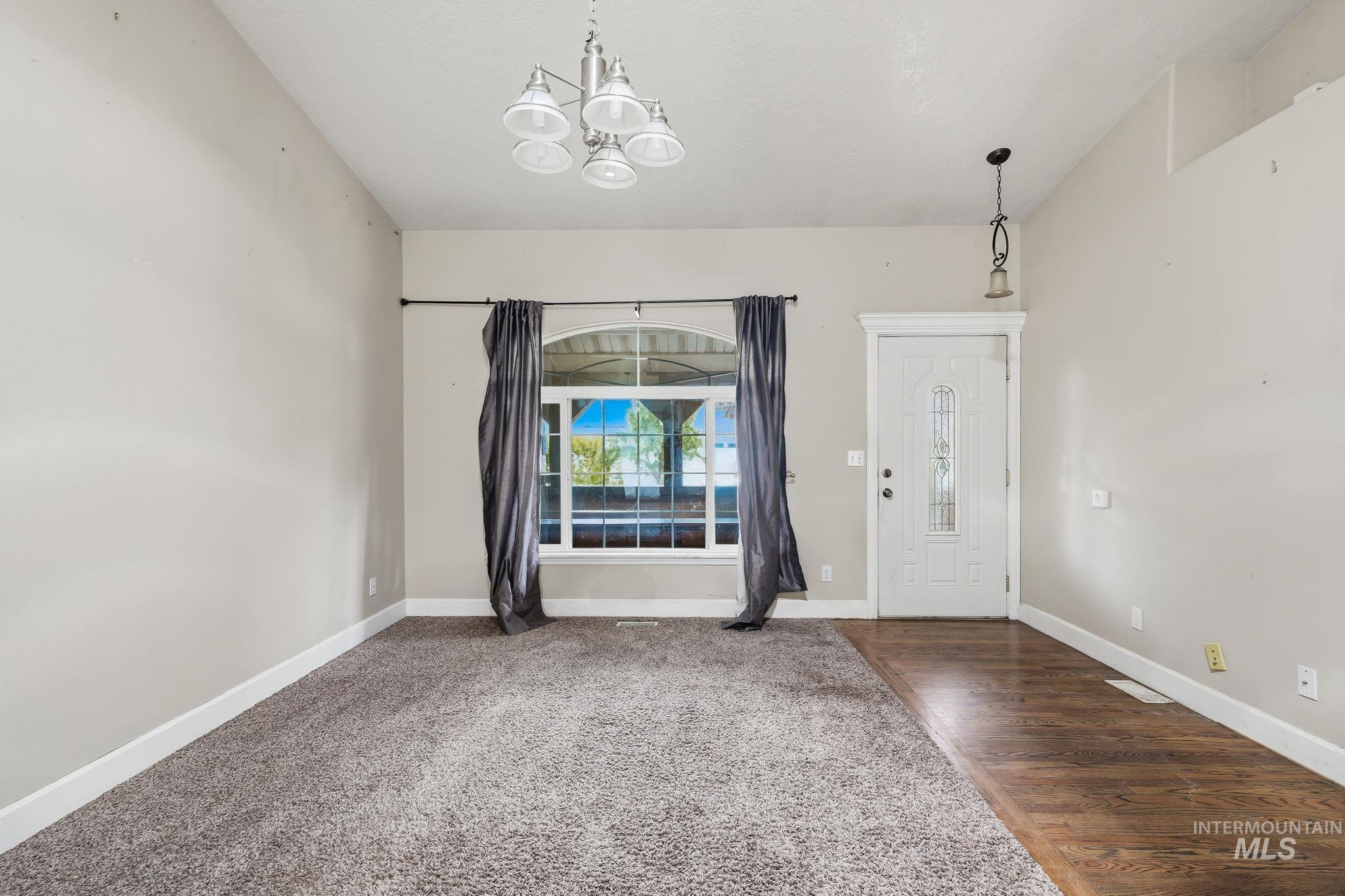 Entryway featuring a white paneled door with decorative glass inserts, a window with an arched transom, and a pendant light fixture