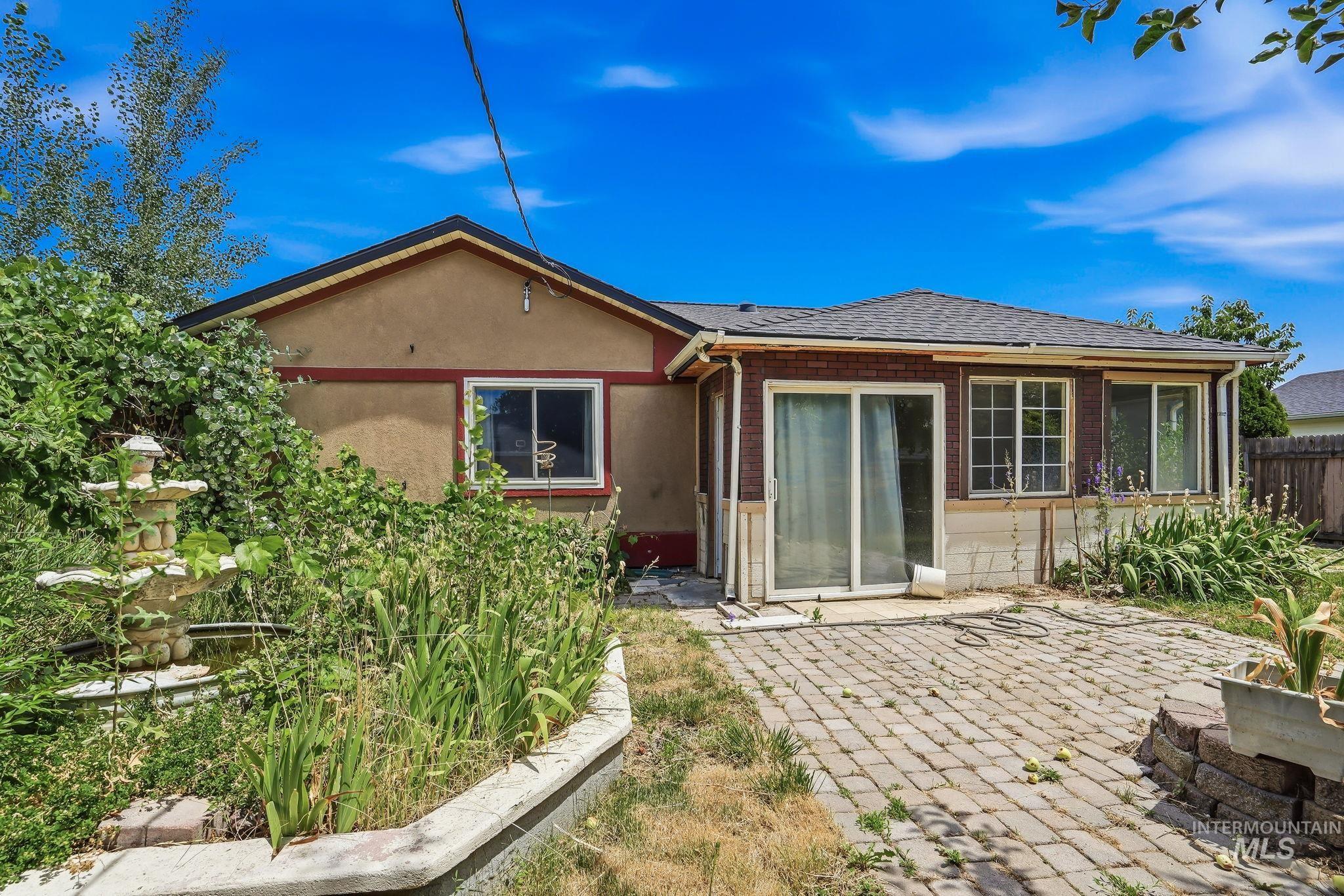 Rear exterior with a paver patio and a stone-look tiered fountain