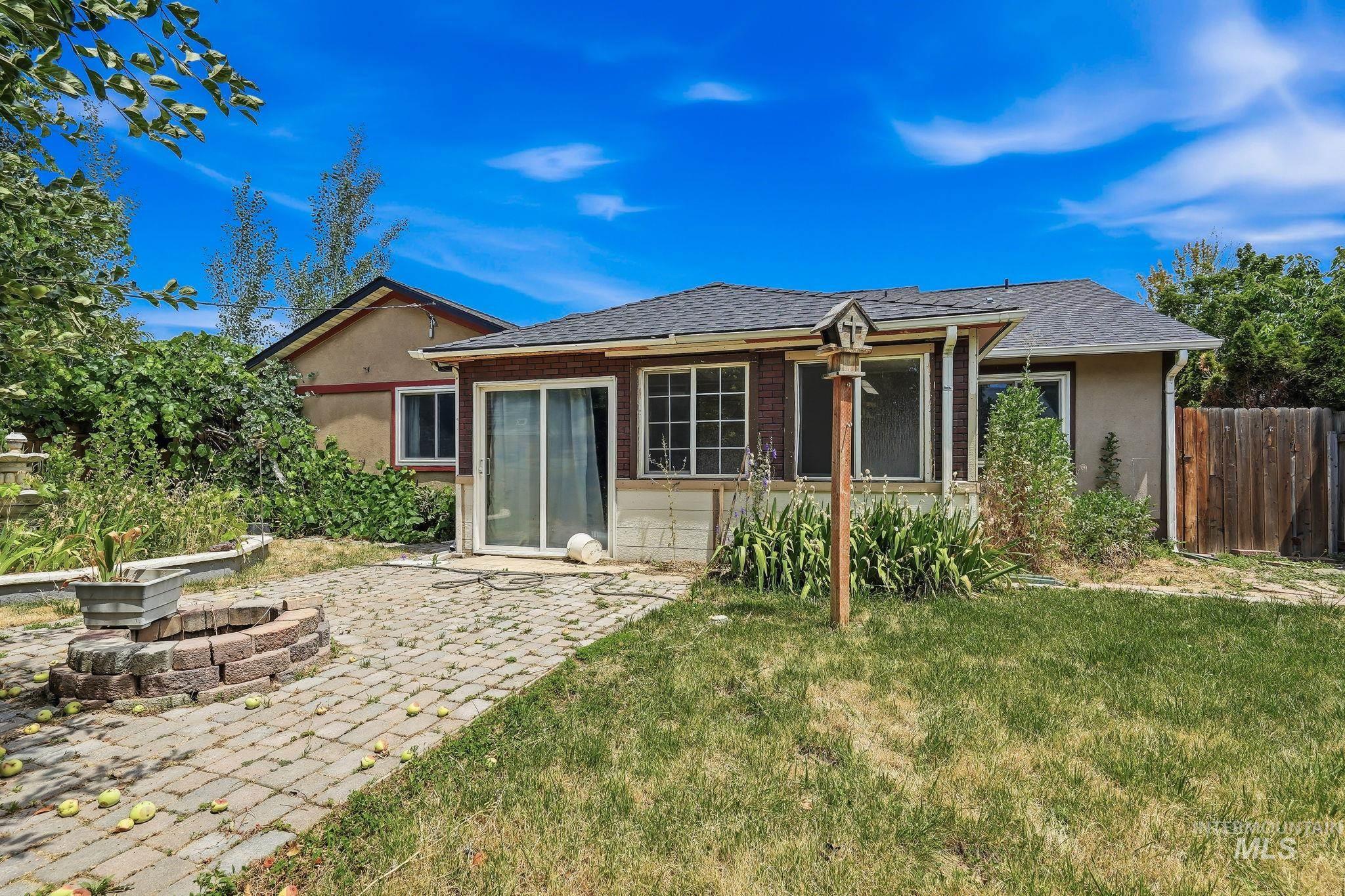 Rear exterior featuring a brick paver patio with an integrated fire pit