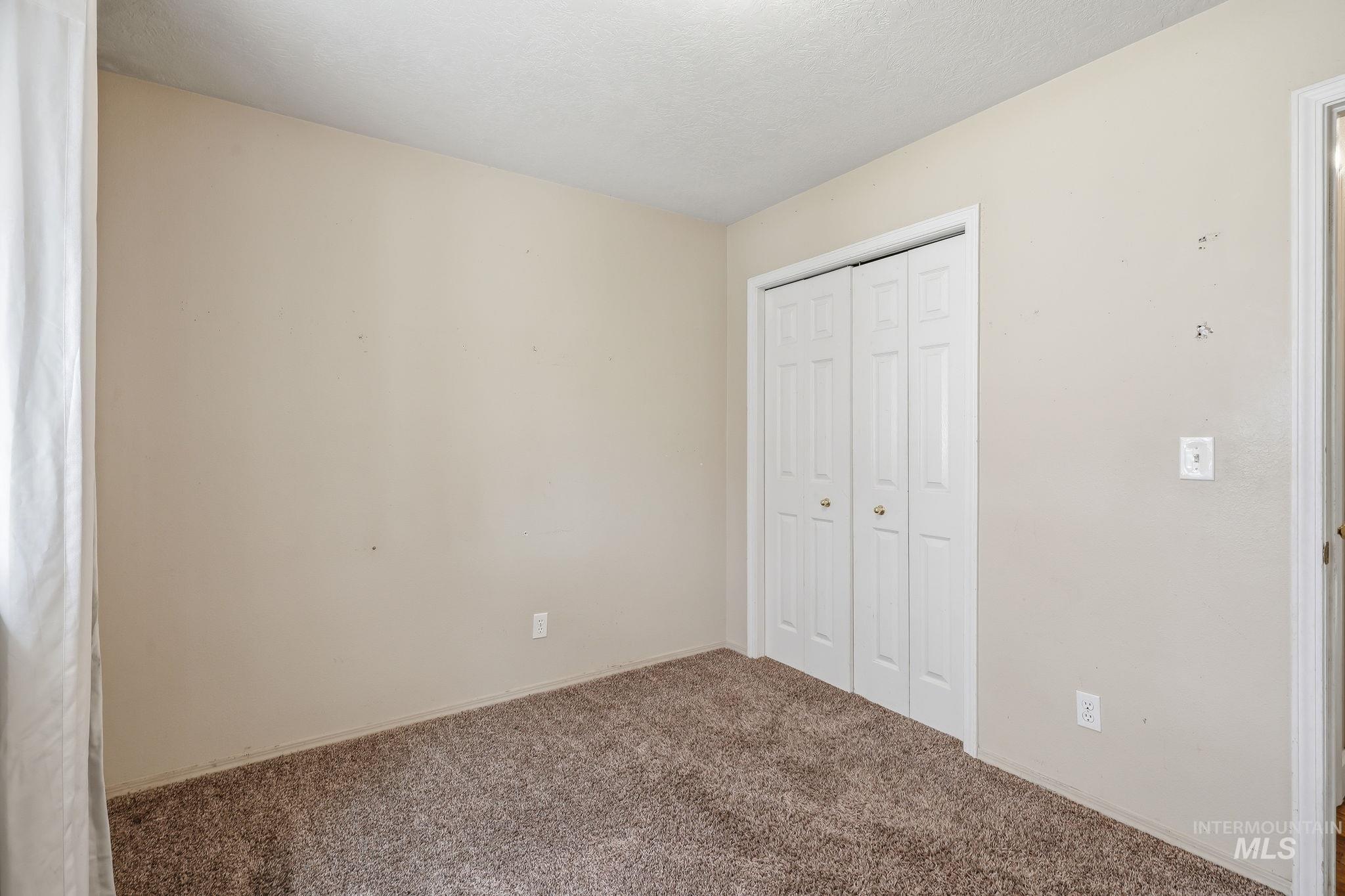 Carpeted interior space featuring neutral wall paint and white bi-fold closet doors