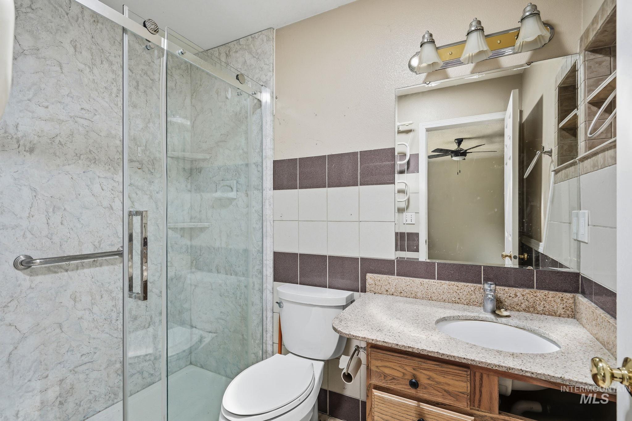 Glass-enclosed shower with a grab bar, featuring a marble-patterned surround