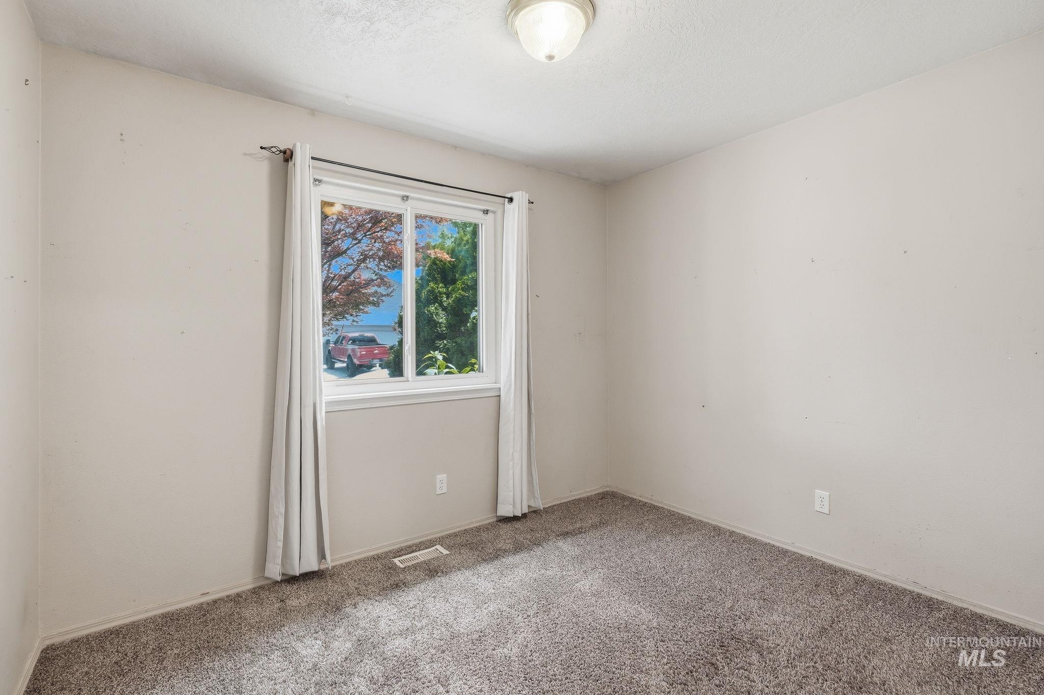 Neutral wall finish, gray carpet flooring, white window trim, and a ceiling-mounted light fixture