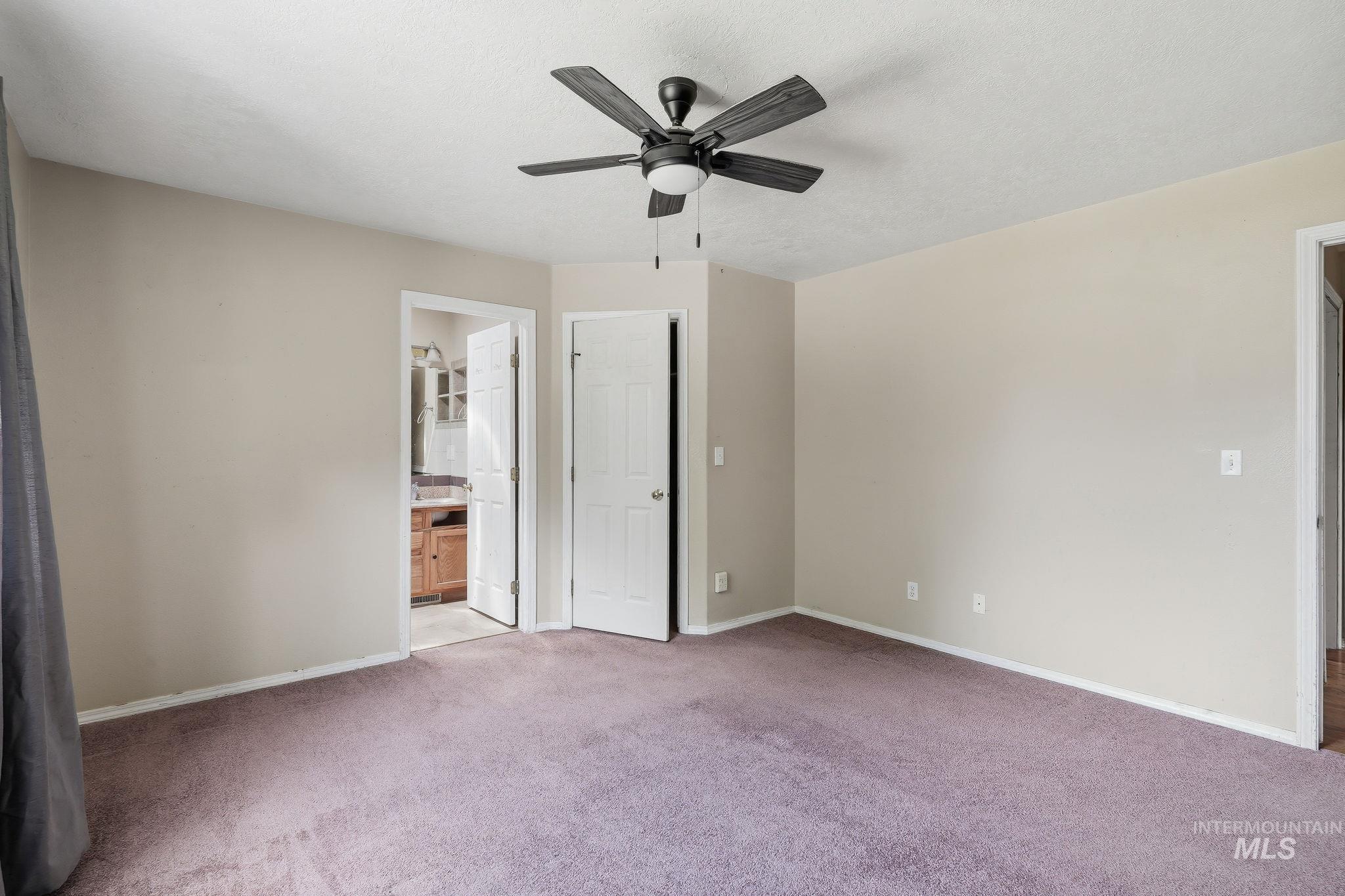 Interior room featuring neutral wall paint, purple-toned carpeting, and a ceiling fan with integrated lighting