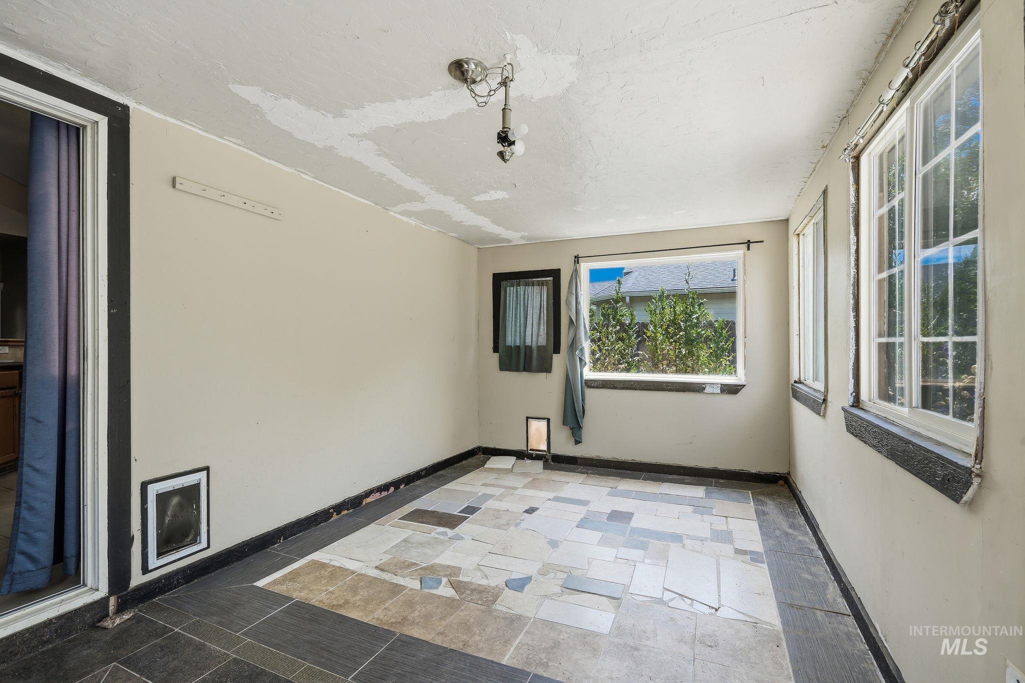 Sunroom featuring multiple windows, a ceiling-mounted light fixture, and a mix of tile flooring