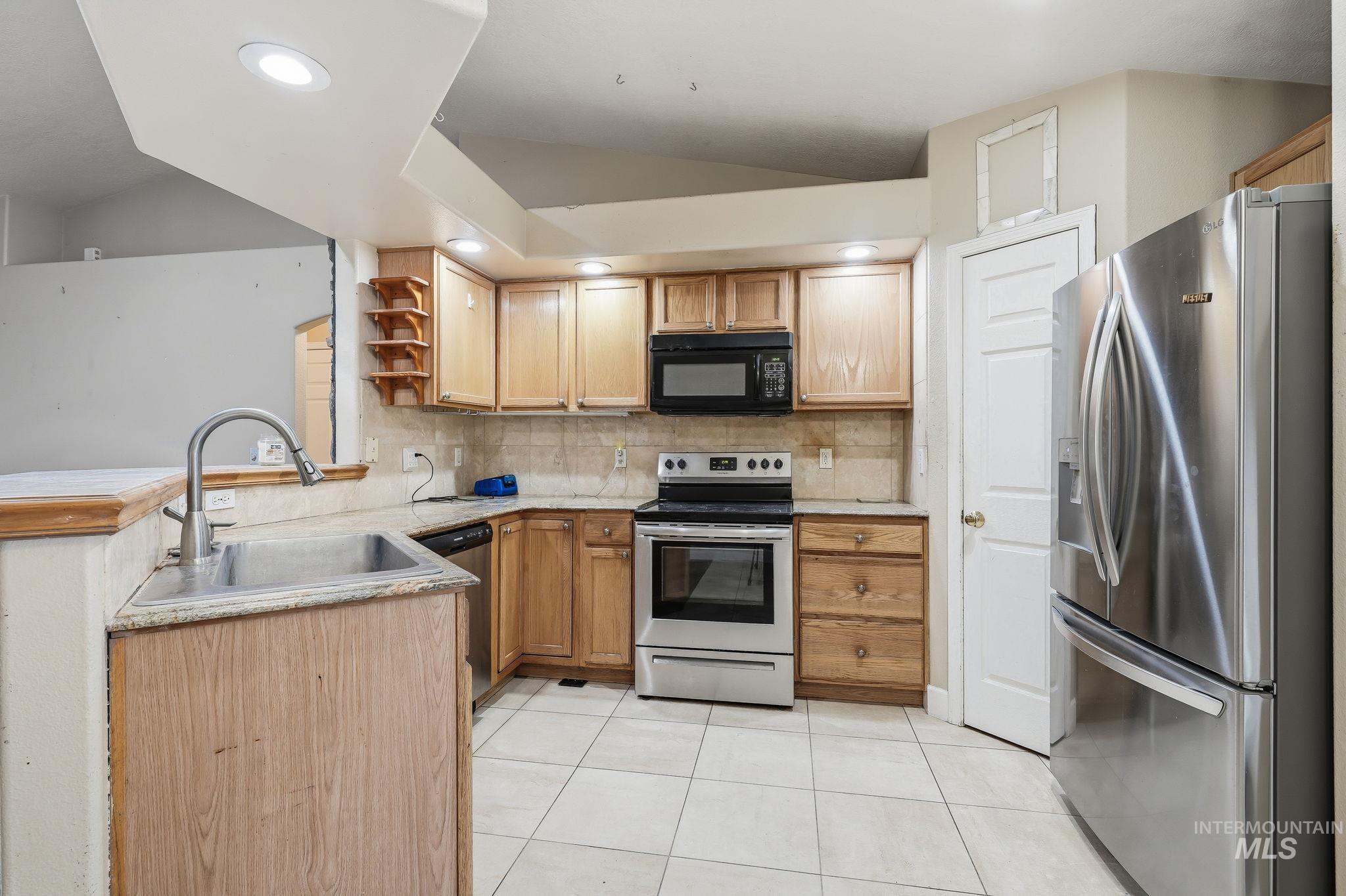 Kitchen featuring wood cabinetry, stainless steel appliances, tile flooring, and recessed lighting